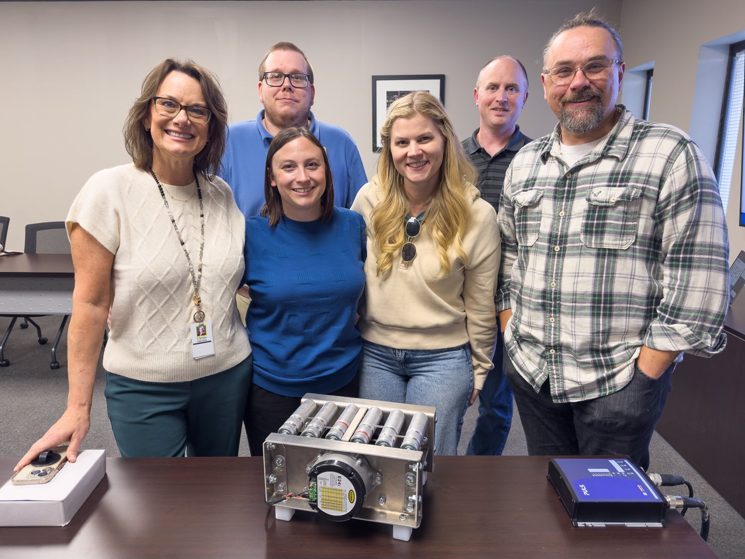Group photo of educators at Hytrol posing in front of a miniature conveyor model
