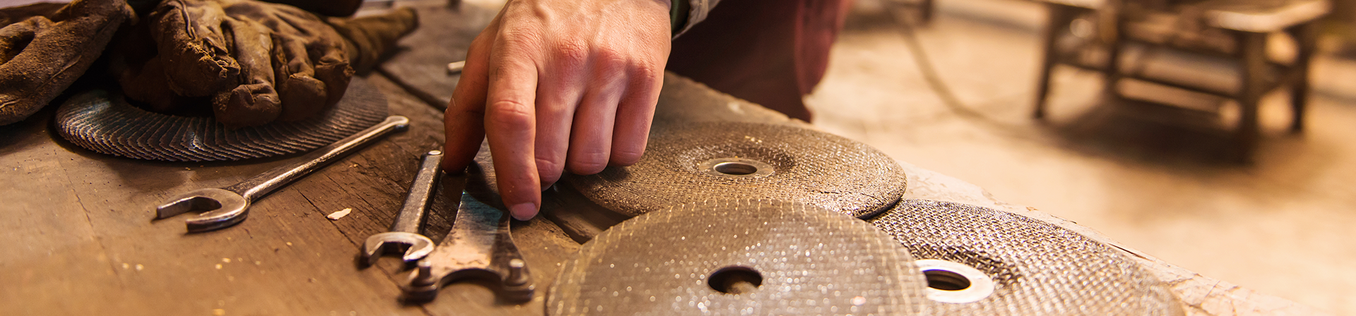 Man's hand picking up a wrench amongst other tools