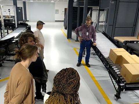 An employee of Hytrol shows teachers a simple conveyor and how it carries boxes