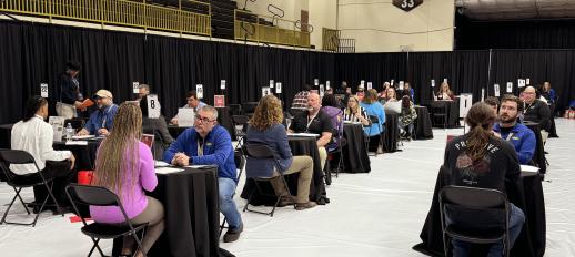 Employers conducting interviews one-on-one with students all throughout a section of a gym