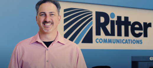 Victor Esposito standing in front of a Ritter Communications sign on the wall